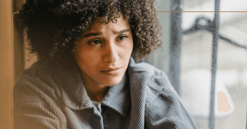 A woman wearing a gray corduroy shirt is looking off camera while crying. There is a brown line framing the image.