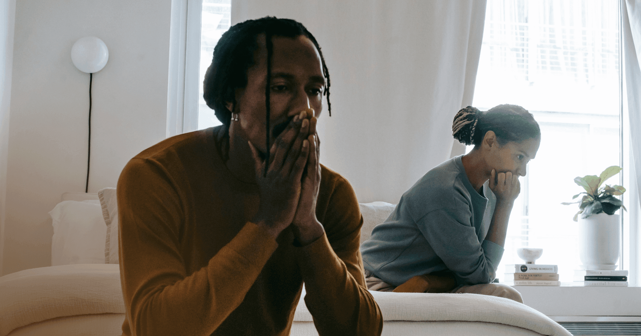 couple with fear of abandonment sitting on a bed not looking at each other